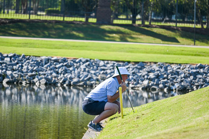 Alabama Golf Association competitor lining up a putt by a pond